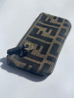 A Fendi monogram zippered pouch in brown and black coated canvas with a dark brown leather zipper pull and a gold-tone Fendi logo medallion.