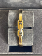 MODEVESTIGE vintage Gucci 1400L gold-plated bangle watch with a minimalist link design on a grey display stand.