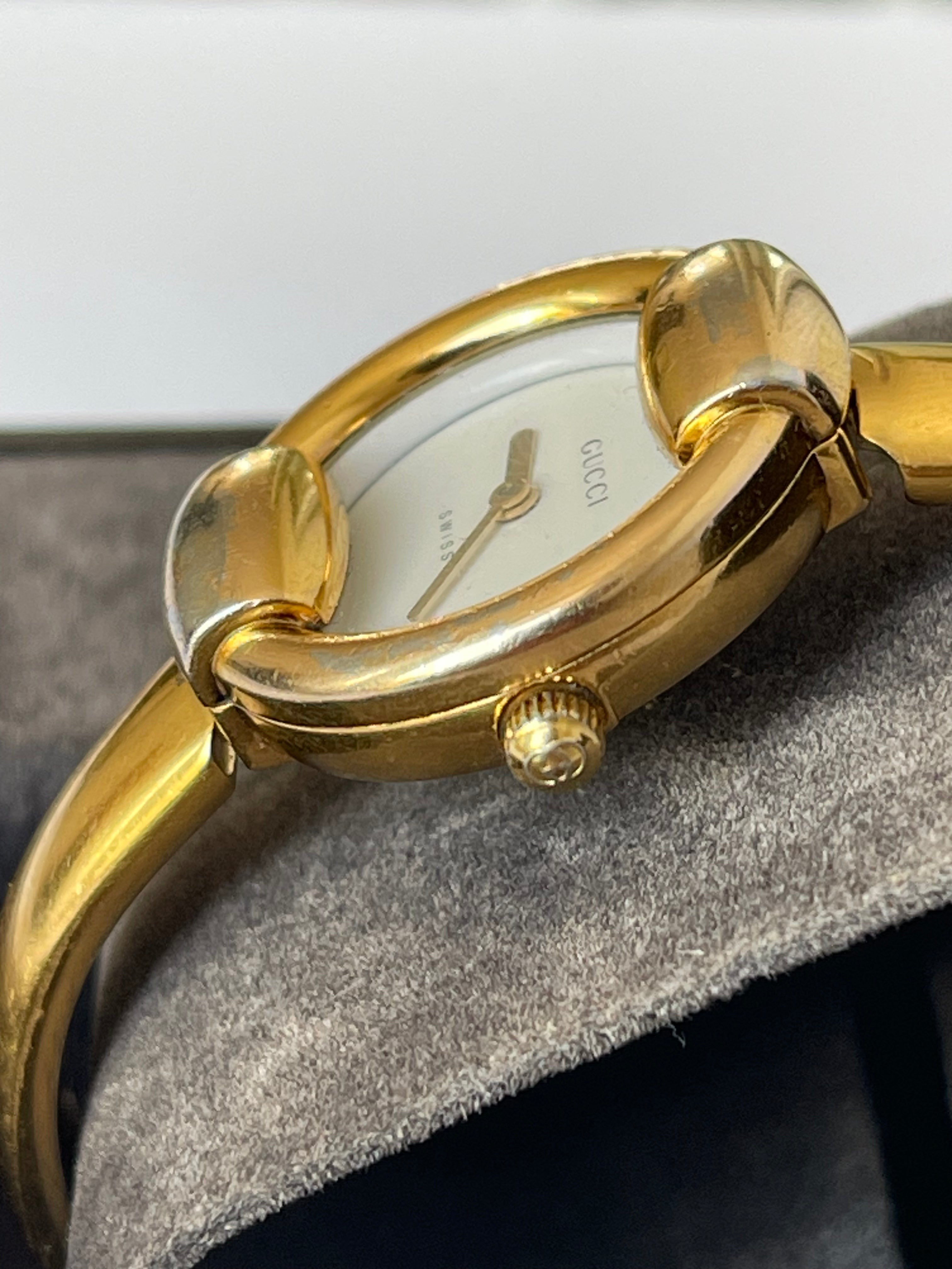 MODEVESTIGE vintage Gucci 1400L gold-plated wristwatch with a white dial, shown in a close-up side profile view.
