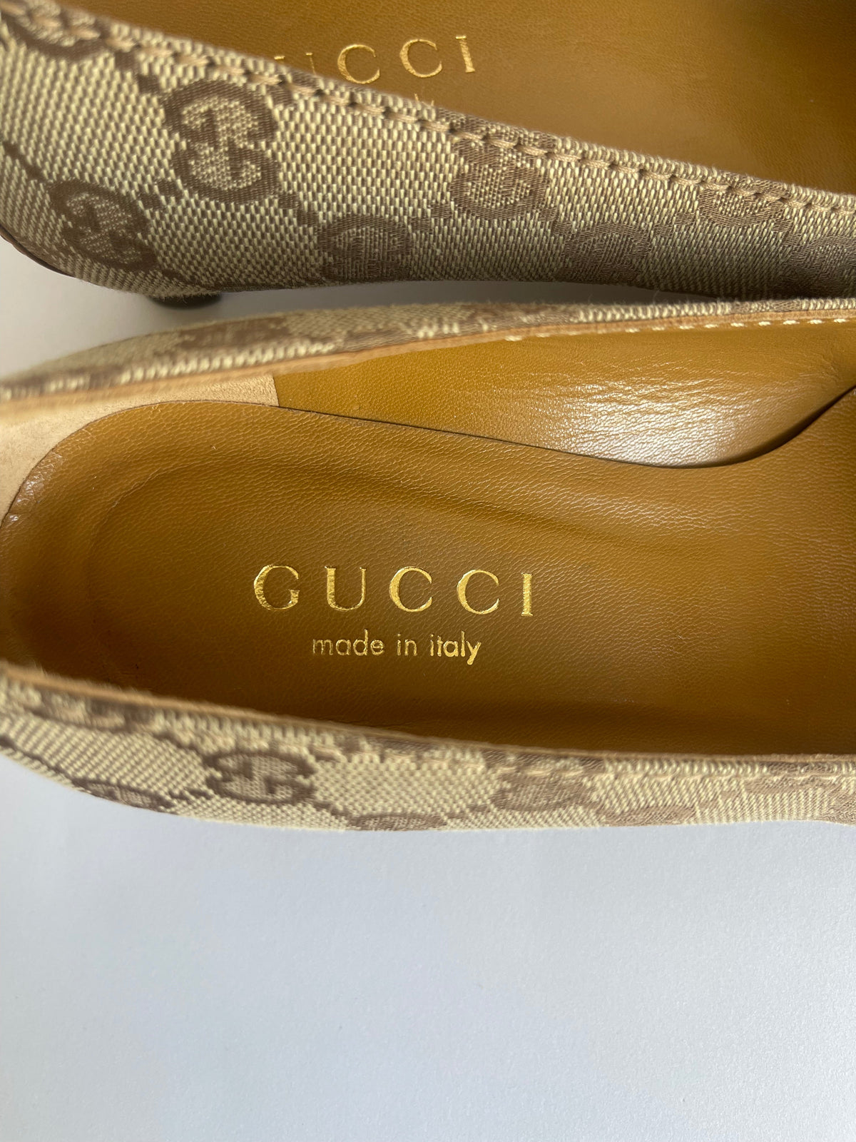 Detalhe interno de scarpin vintage Gucci da MODEVESTIGE em lona bege GG e couro, com palmilha dourada.