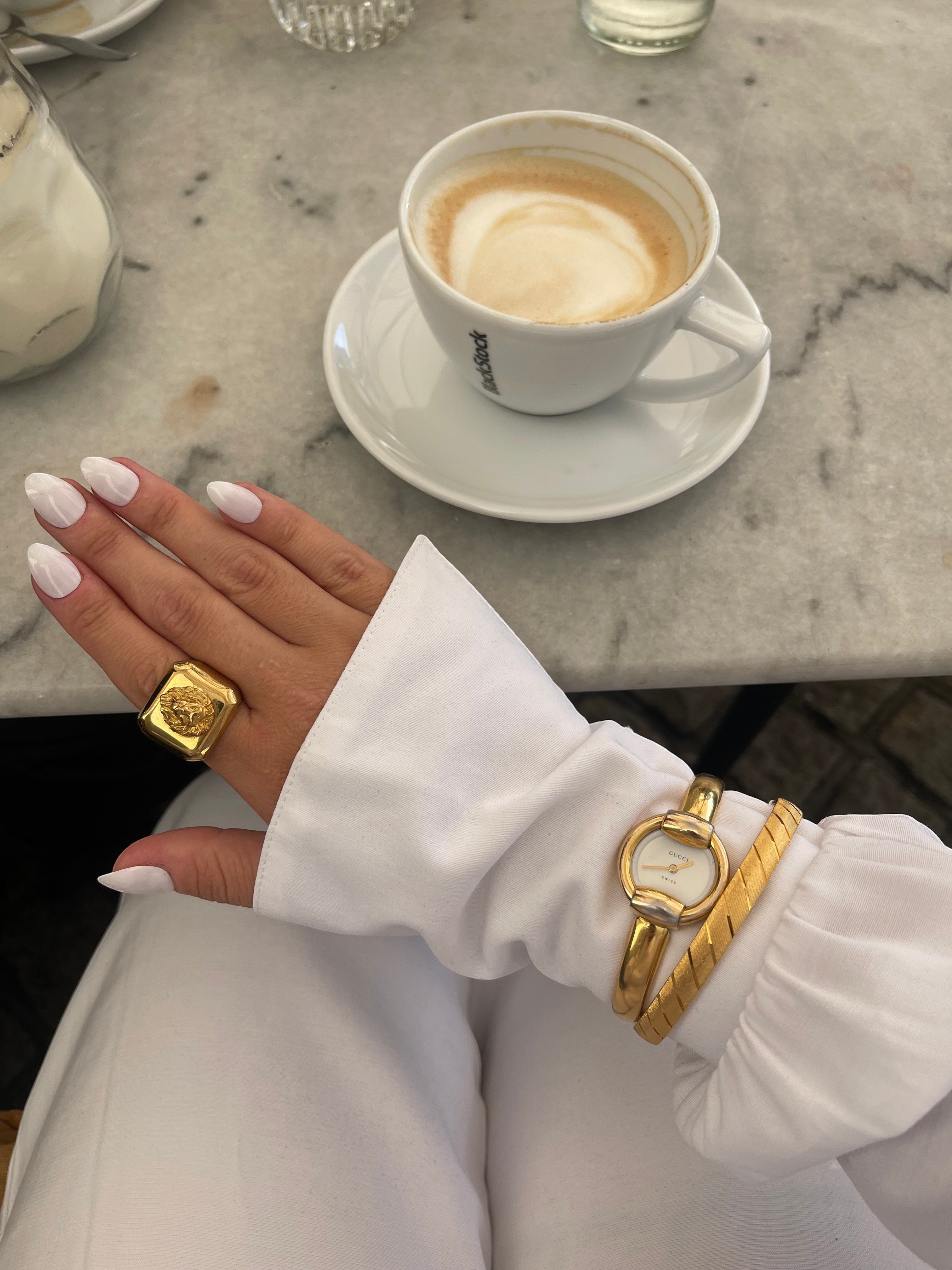 MODEVESTIGE vintage Gucci 1400L gold-plated watch with white dial worn on wrist with a gold statement ring