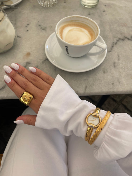 MODEVESTIGE vintage Gucci 1400L gold-plated watch with white dial worn on wrist with a gold statement ring
